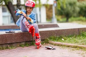 niña en patines se pone protección foto