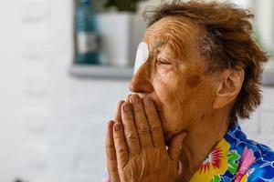 Faithful old senior grandmother pray with hope faith holding hands together sit on sofa alone at home, religious elderly woman believer christian with eyes closed say gratitude worship prayer concept photo