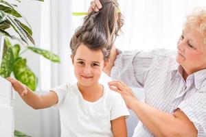 adorable playful little child girl with happy middle aged nanny grandma at home. Cute small preschool granddaughter with excited elderly grandmother. photo