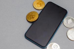 moneda bitcoin con teléfono sobre fondo gris foto