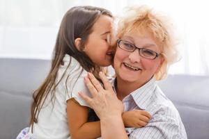 adorable playful little child girl with happy middle aged nanny grandma at home. Cute small preschool granddaughter with excited elderly grandmother. photo