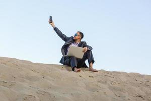 Businessman sitting alone in the empty desert photo