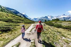 Hiking - hiker woman on trek with backpack living healthy active lifestyle. Hiker girl walking on hike in mountain nature landscape in Swiss alps, Switzerland. photo