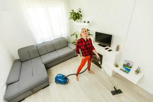 mujer limpiando la aspiradora de suelo en el moderno salón blanco foto