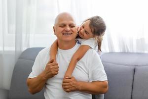 retrato de abuelo con nieta relajándose juntos en el sofá foto