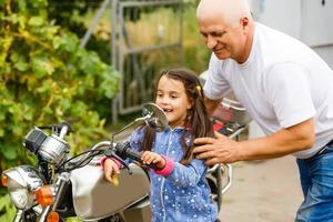 feliz abuelo y su nieta cerca de la bicicleta sonriendo foto