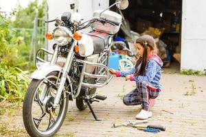 little girl repairing a motorcycle, Student girl in motorbike mechanics photo