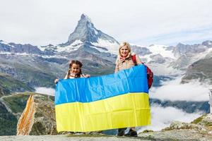 mother and daughter with Ukrainian flag in the mountains of switzerland photo
