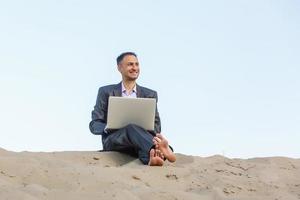 Businessman working and using a laptop and phone in a desert photo