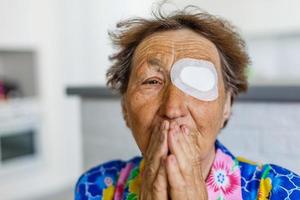 elderly woman with a sore eye prays photo