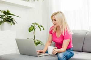 young woman with laptop works at home photo