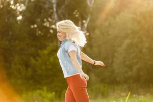 Attractive young woman enjoying her time outside in park with sunset in background. photo