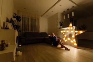 Young sexy woman in dark interior with star light on background. Camera angle view. photo