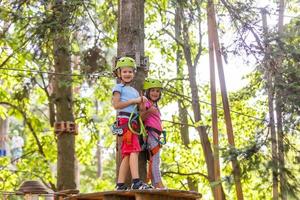 adventure climbing high wire park - children on course rope park in mountain helmet and safety equipment photo