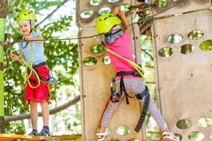 niños pequeños felices en un parque de cuerdas en el fondo de madera foto