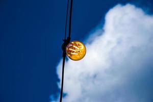 primer plano de un filamento de estilo edison en una bombilla de luz contra un cielo nublado. crisis de energía. foto