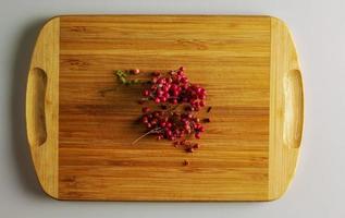 Pink peppercorns. Aromatic spice for food. Background of dried pink pepper seeds on a wooden kitchen board. photo