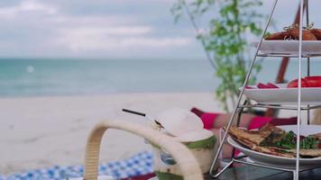 Picnic basket with food and coconut juice on the beach. Clear skies and white sandy beaches with the sound of waves and sea view. Concept relax and travel Samui province. video