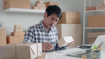 online business owner is checking the validity of packages before delivery. owner is writing down the product codes in a book to check the order list and inventory. Shipping management concepts. video