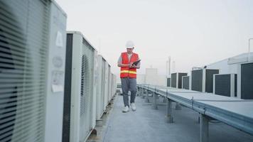 Asian maintenance engineer recheck works on the roof of factory. contractor  inspect compressor system and plans installation of air condition systems in construction site of modern buildings. video