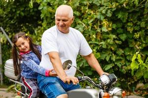 feliz abuelo y su nieta cerca de la bicicleta sonriendo foto