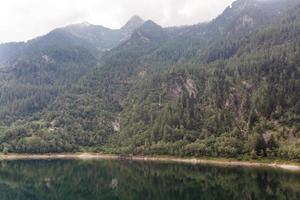 alpine high mountain lake, coniferous woods are reflected in the water, Antrona valley Campliccioli lake, Italy Piedmont photo