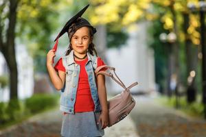 Authentic shot of cute little elegant girl with graduation hat is smiling during ceremony. photo