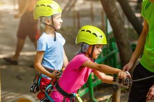 parque de cuerdas de escalada de aventura - niños en el parque de cuerdas del curso en casco de montaña y equipo de seguridad foto