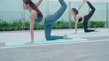 mujer delgada practicando yoga en el balcón de su condominio. mujer asiática haciendo ejercicios por la mañana. equilibrio, meditación, relajación, calma, buena salud, feliz, relax, concepto de estilo de vida saludable video