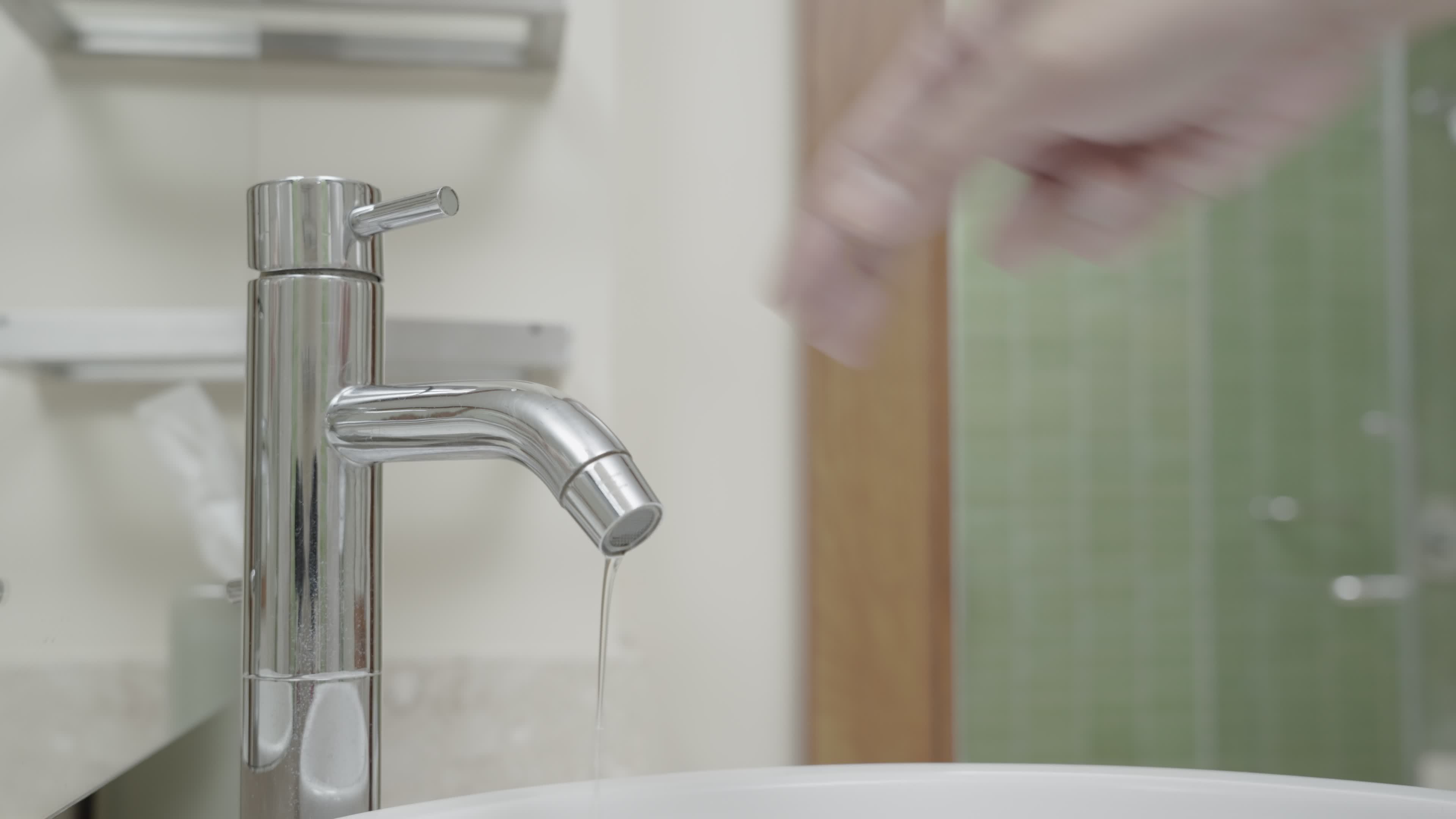 The faucet in the bathroom with running water. Man keeps turning off