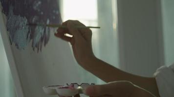 artista profesional usa pincel en arte abstracto para crear una obra maestra. pintura de pintor con acuarelas o aceite en casa de estudio. bella mujer disfruta pintando como hobby. recreación laboral video