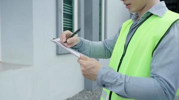 inspector o ingeniero está inspeccionando e inspeccionando un edificio o casa usando una lista de verificación. ingenieros y arquitectos o contratistas trabajan para construir la casa antes de entregársela al propietario. video