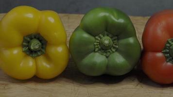 drie zoet paprika's. drie kleurrijk klok paprika's rood geel en groen kleuren in een rij. video