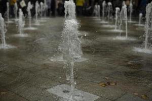 Fountain in city. Water jets in area. Flow of water. photo