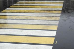 Pedestrian crossing in rain. Puddle on pavement. Wet road details. photo