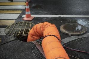 tubo naranja desciende en la escotilla. reparación de alcantarillado. bombeo de aguas residuales. suministro de aire. foto