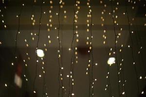 Garlands on glass. Small bulbs on wires. Lights on window. photo