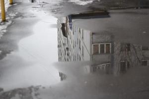 Puddle on road in city. Water on asphalt. Details of city in winter. photo