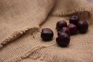 purple cherries placed on a cloth sack photo