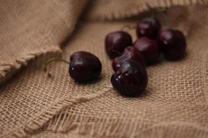 purple cherries placed on a cloth sack photo