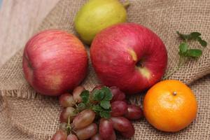 Fruits with vitamin C that are beneficial to the body. Place on sackcloth - orange, grape, apple, guava photo