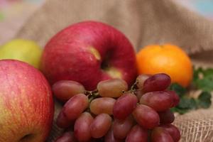 Fruits with vitamin C that are beneficial to the body. Place on sackcloth - orange, grape, apple, guava photo