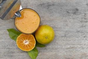 Orange juice in glass and fresh citrus around with Juicer hand press squeezer fruit on wood table photo