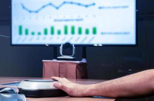 Man hand is pressing the microphone button to speak with Presentation meeting on television in Video conference meeting room photo