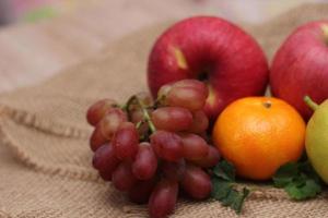 frutas con vitamina c que son beneficiosas para el organismo. colocar sobre tela de saco - naranja, uva, manzana, guayaba foto