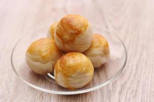 Chinese food moon cake or Chinese Pastry served on a glass plate placed on a light brown wooden table. photo