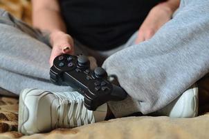 A young girl plays video games with a black joystick with many b photo