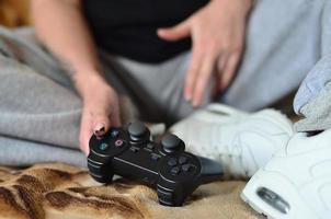 A young girl plays video games with a black joystick with many b photo