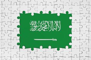 bandera de arabia saudita en el marco de piezas de un rompecabezas blanco con la parte central faltante foto