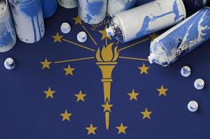 Indiana US state flag and few used aerosol spray cans for graffiti painting. Street art culture concept photo